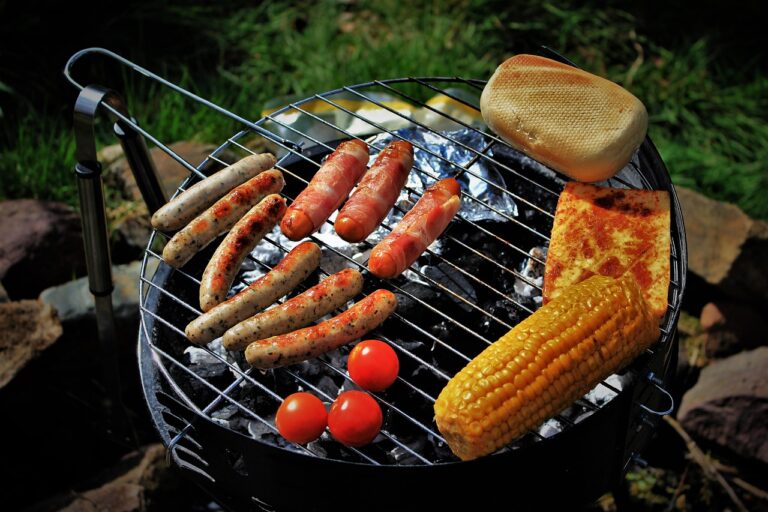 Holzkohlegrill im Garten mit offener Flamme und sicherem Abstand zu Pflanzen