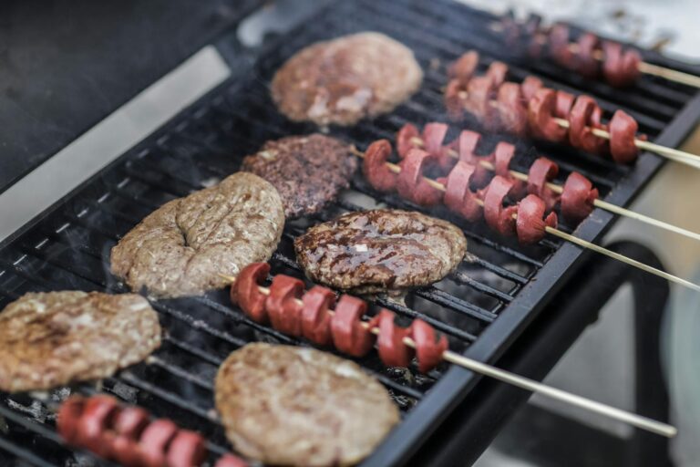 Smoker und Gasgrill im Vergleich mit Grillgut und Grillzubehör auf Holzuntergrund