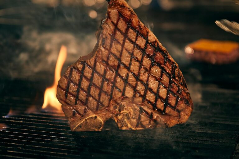 Saftiges Ribeye Steak perfekt gegrillt auf heißem Grillrost mit Grillzange